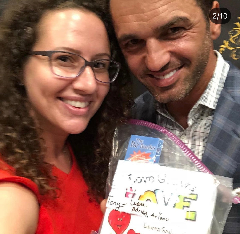 Lauren Grabois Fischer smiling with International Dance Director and World Champion with Fred Astaire Dance Studios, Tony Dovolani  holding her children's book 'Love Grows Love'
