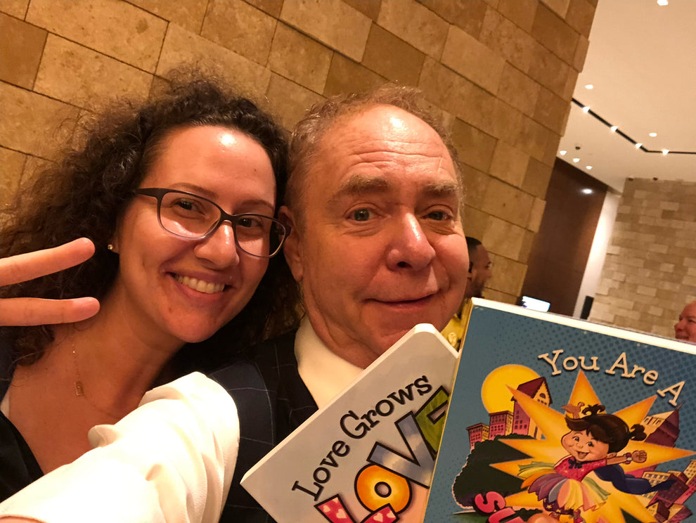 Lauren Grabois Fischer with a Joseph Teller of Penn and Teller holding her books 'Love Grows Love' and 'You Are a Superhero,' celebrating empowerment and kindness