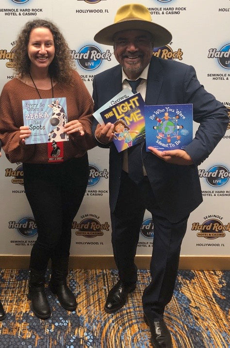 Lauren Grabois Fischer with a Joseph Teller of Penn and Teller holding her books 'Love Grows Love' and 'You Are a Superhero,' celebrating empowerment and kindness